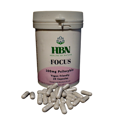 White HBN Focus bottle with pink label, 20 capsules spilled in front. Label reads 100mg Psilocybin, vegan-friendly.